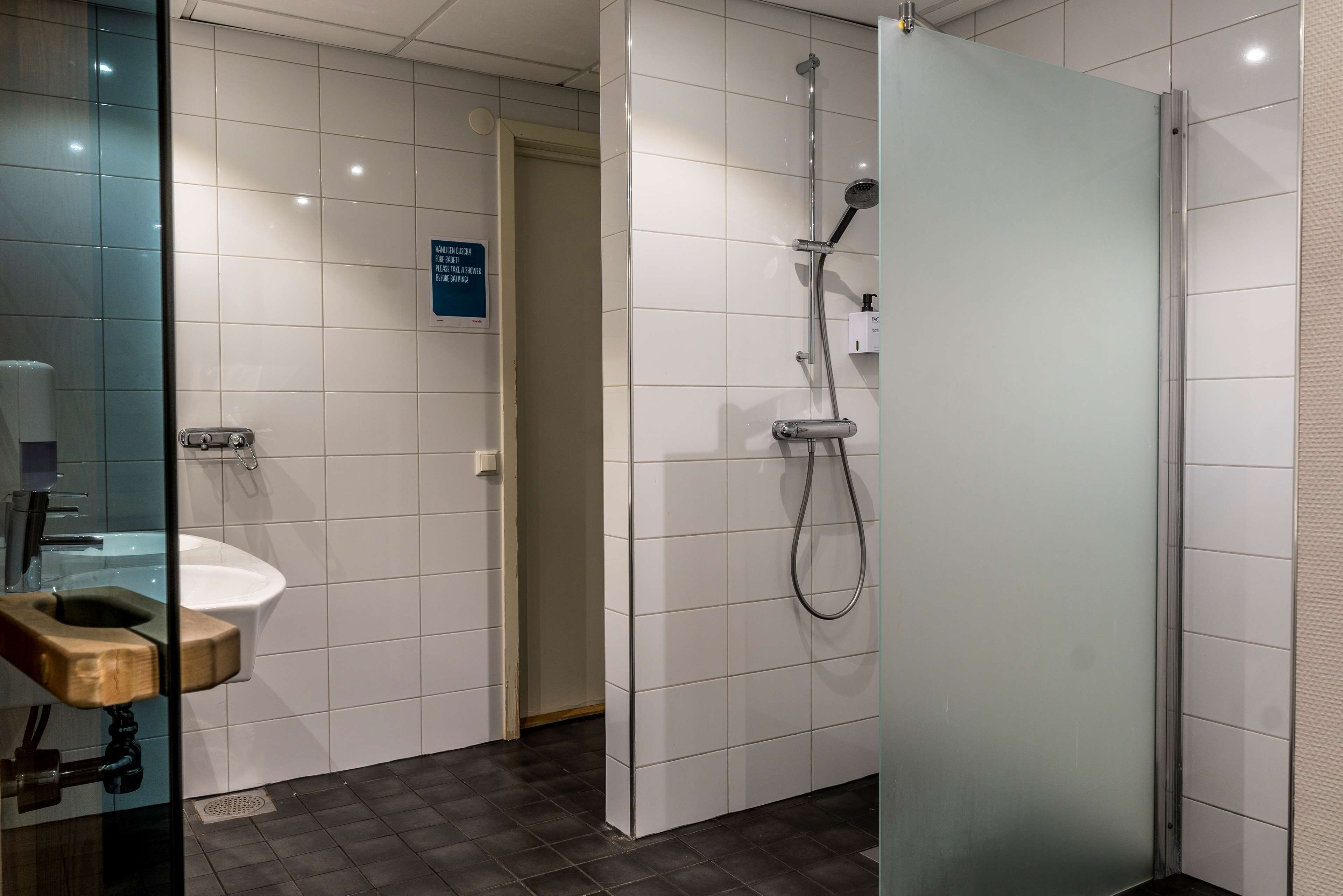 Un baño moderno con separador de vidrio, un lavabo con encimera de madera y zona de ducha.