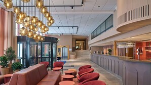 Un lobby moderno con área de descanso, mostrador de recepción y escalera.