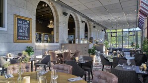Un restaurante con techos altos, ventanas arqueadas y una variedad de mesas dispuestas.