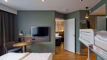Une chambre d’hôtel équipée d’un lit, d’un bureau, d’une chaise, d’une télévision et d’un lit superposé.