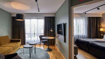 A hotel room with a sofa, a round table, a TV, and a bed.