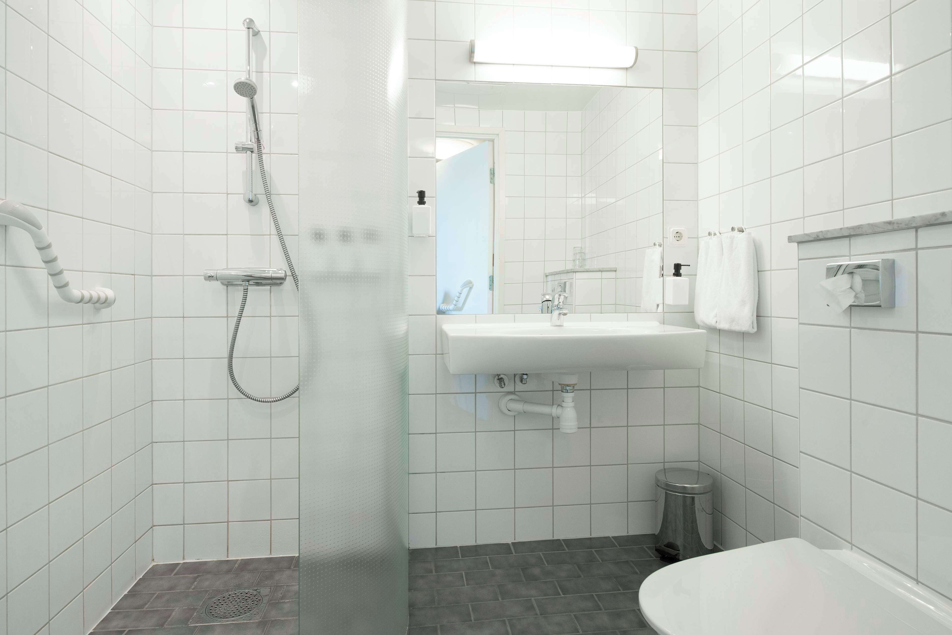 A modern bathroom with a shower, sink, and toilet.