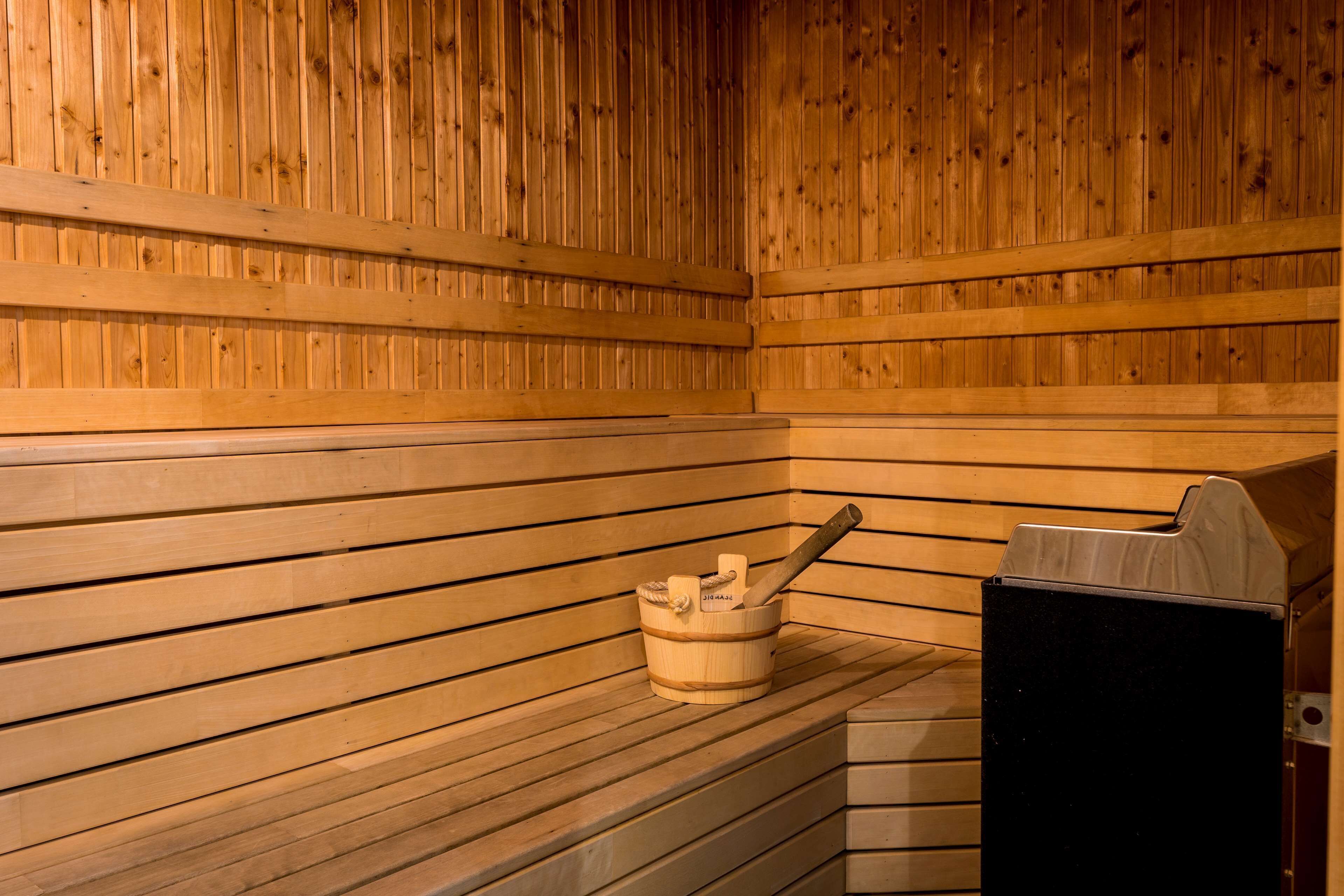 Una sauna de madera con bancos y un balde de madera con un mazo.