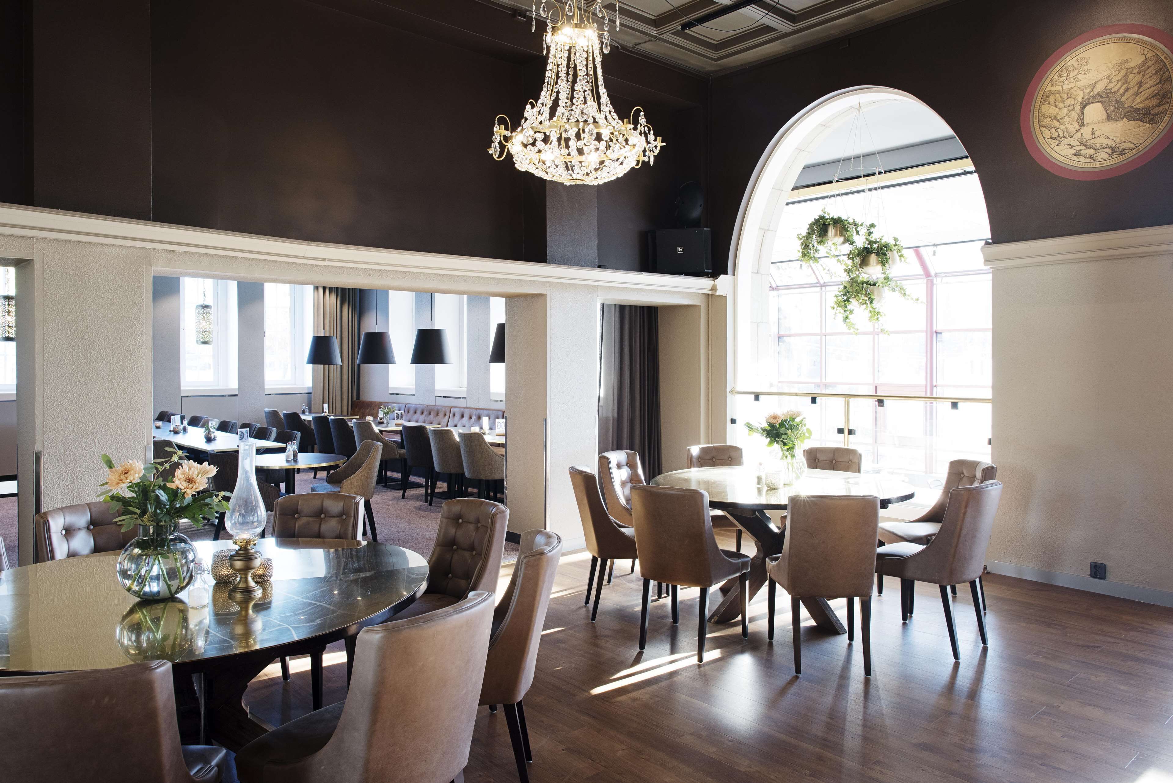 A spacious dining area with a chandelier, large windows, and a view of the dining room in the background.