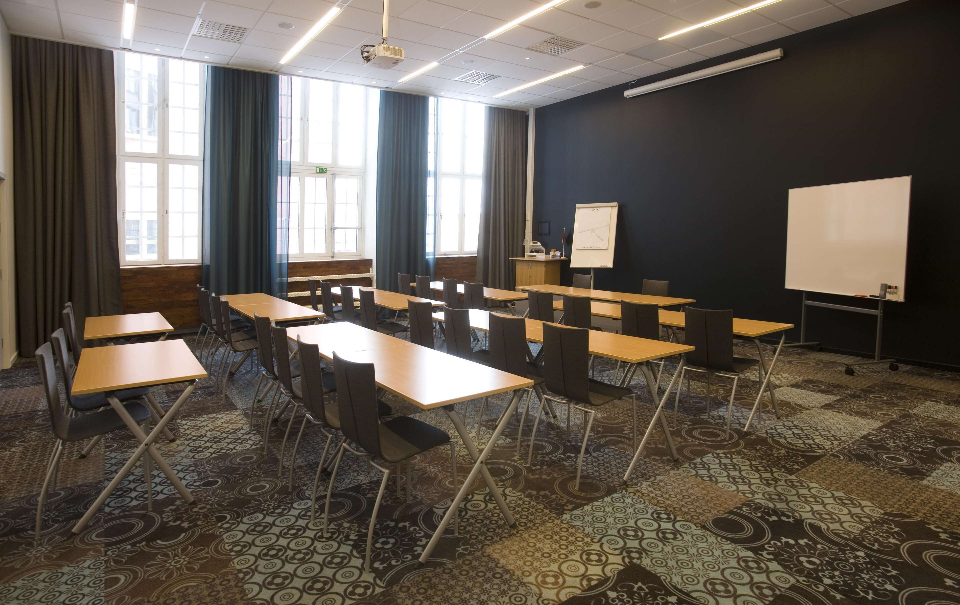 A conference room with a large table, chairs, a whiteboard, and a projector screen.