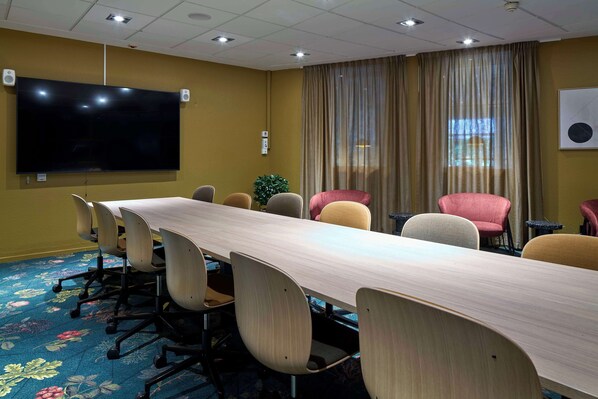 A conference room with a long table, chairs, a flat-screen TV, and a large window with curtains. - Scandic Swania (Trollhattan)