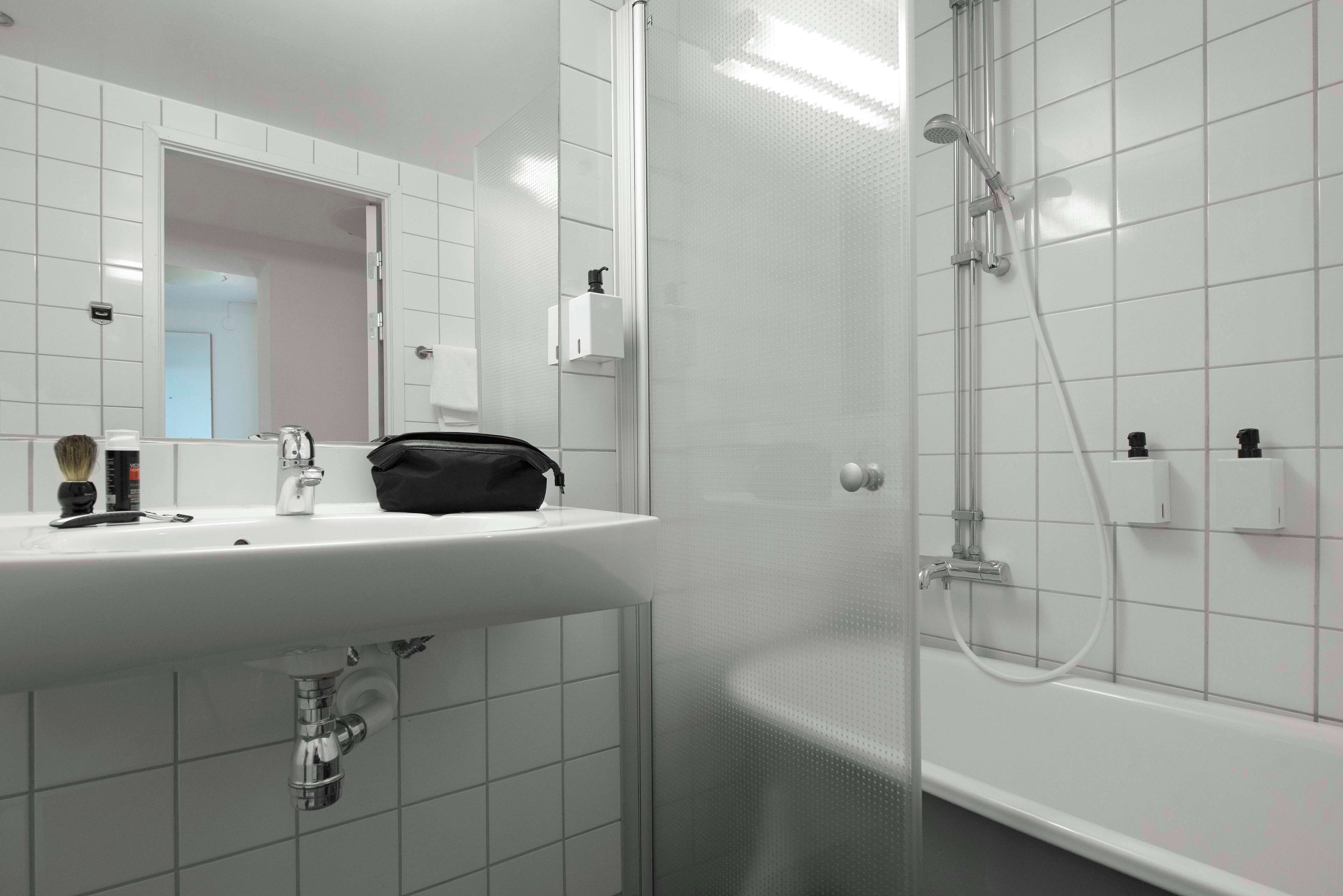 A modern bathroom with a white sink, mirror, and shower.