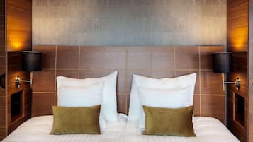 A hotel room with a large bed, two bedside lamps, and a textured wall.