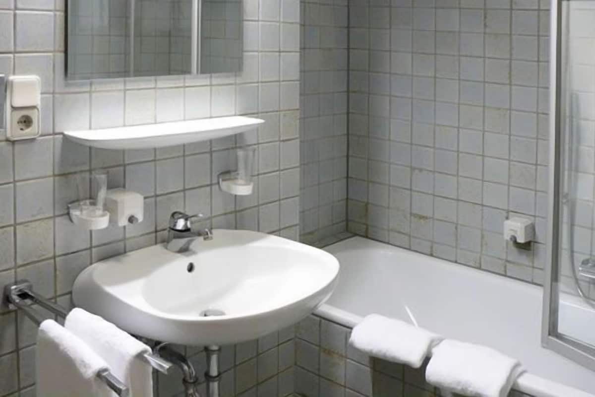 A bathroom with a sink, mirror, and shower.