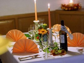 Una mesa dispuesta para una comida, con velas, vino y adornos decorativos.