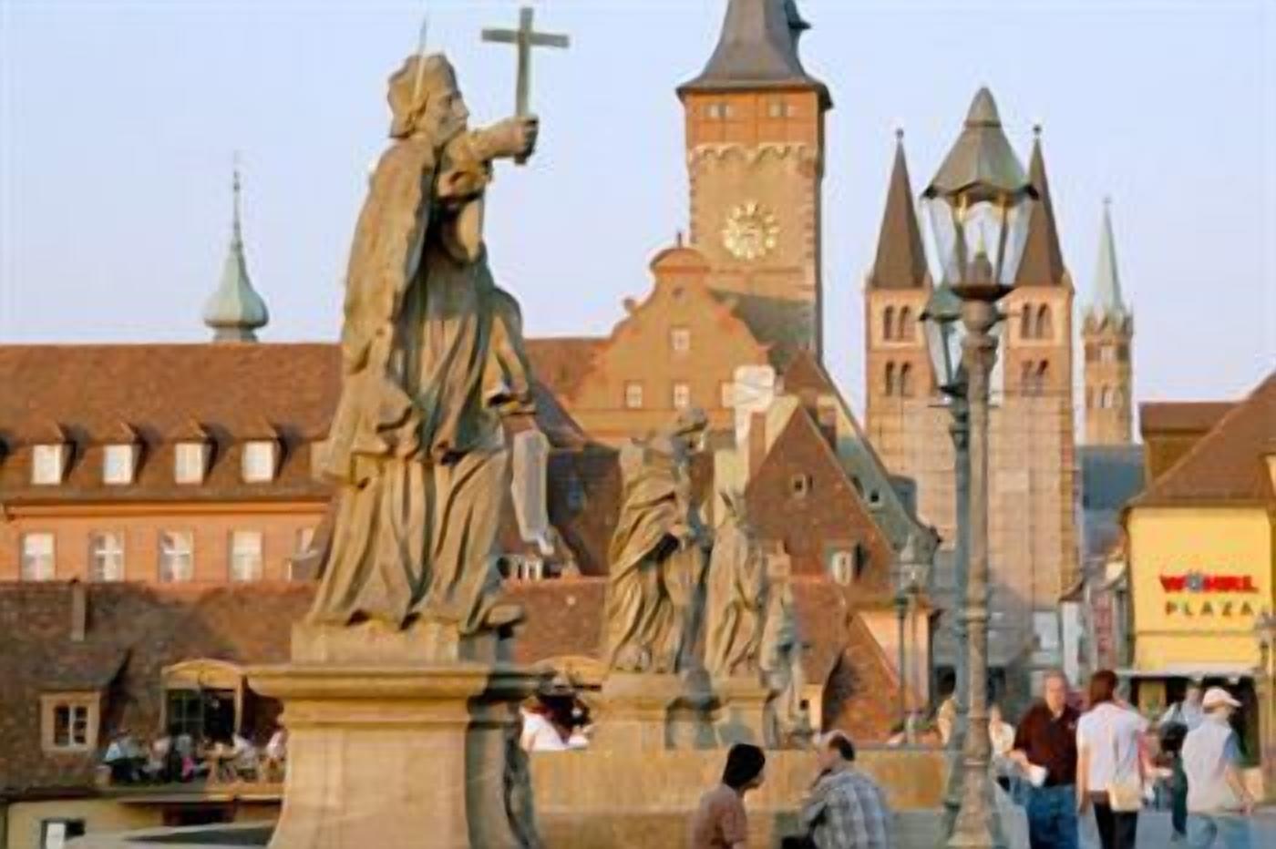 Una plaza histórica con estatuas y un campanario.