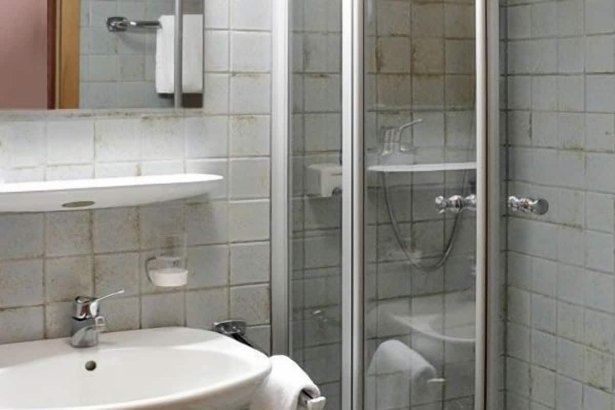A bathroom with a white sink, a mirror, and a glass-enclosed shower area.