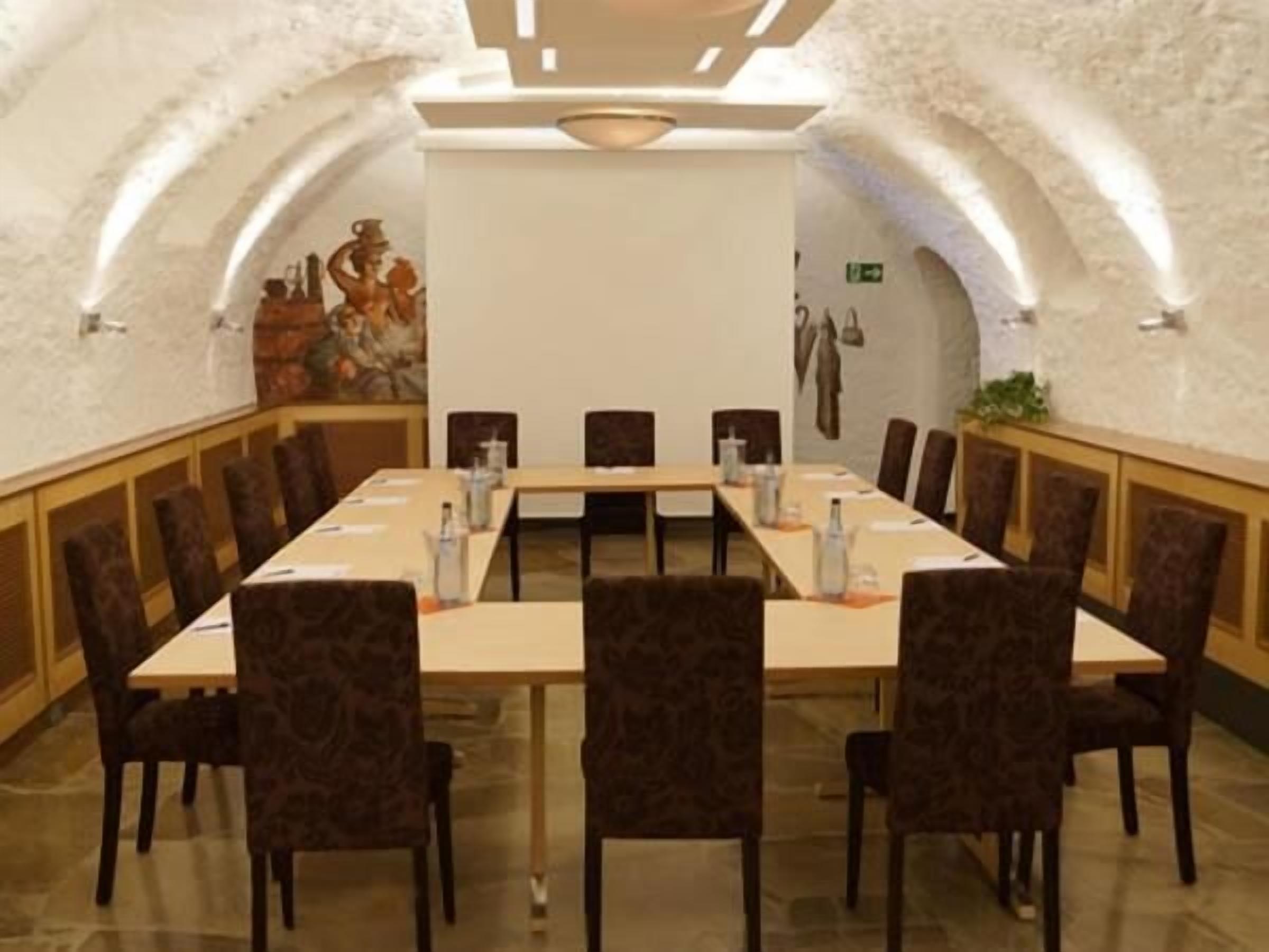 Una sala conferenze con un lungo tavolo, sedie e un quadro appeso al muro.