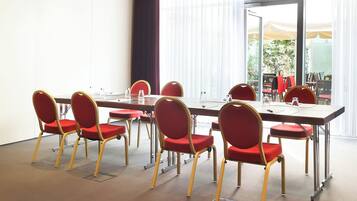 A conference room with a long table and red chairs with gold frames.