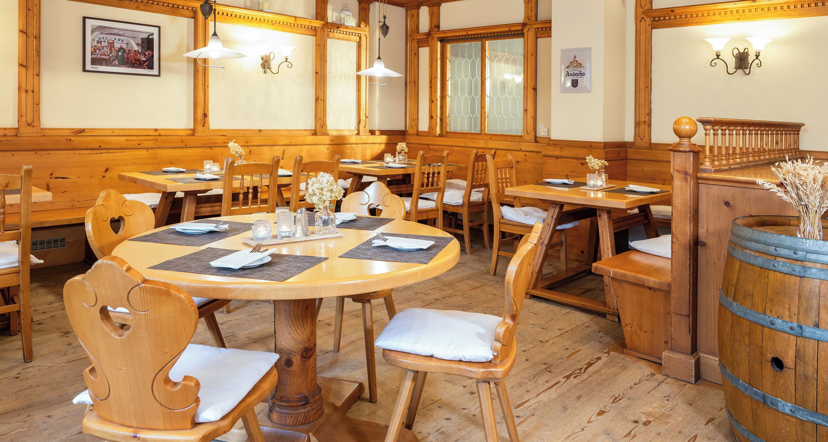 Un restaurante con mobiliario de madera, mesas redondas y un ambiente rústico.