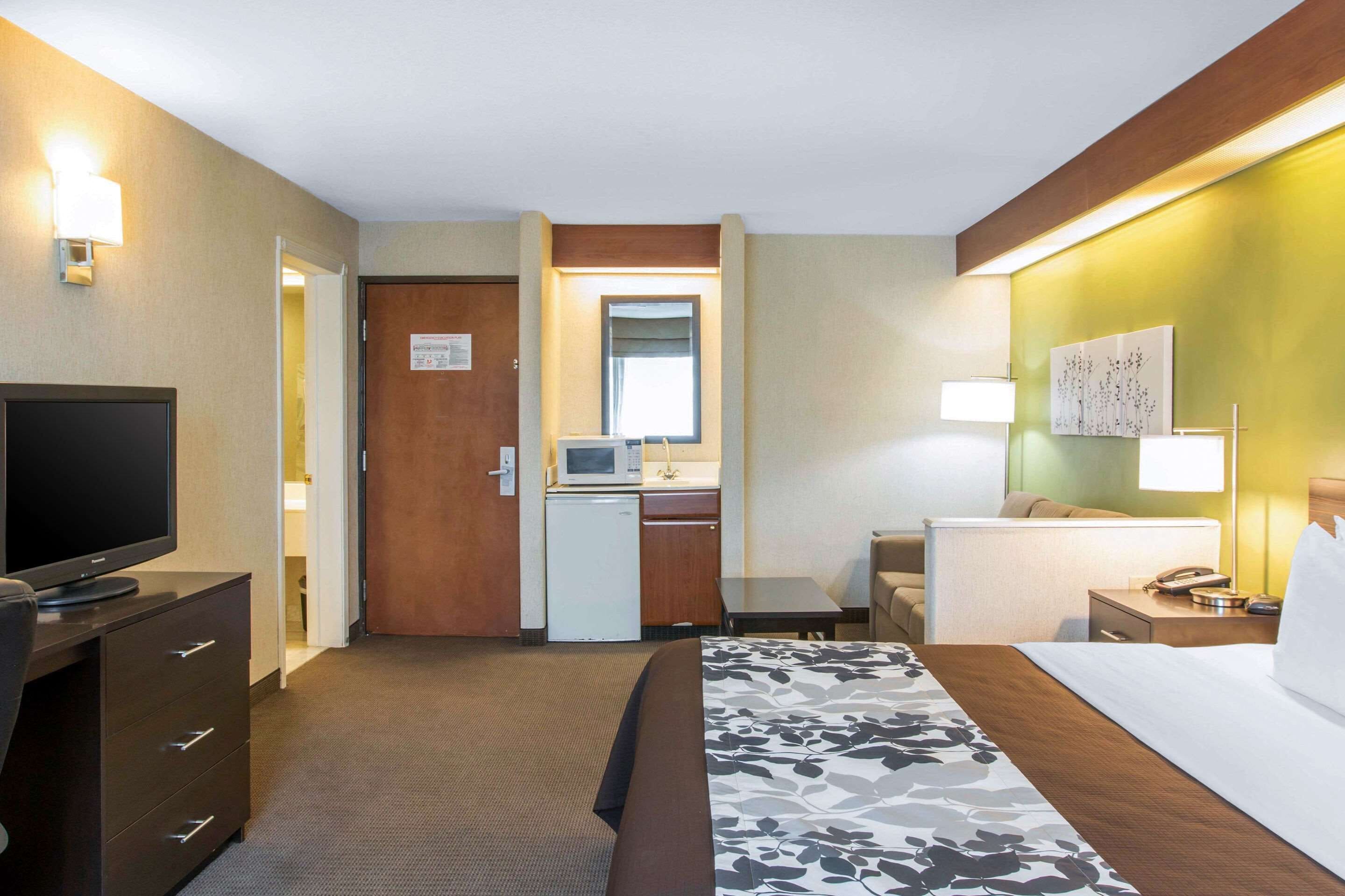 A hotel room with a bed, a desk with a computer, a television, and a microwave.