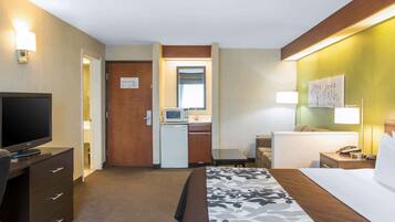 A hotel room with a bed, a desk with a computer, a television, and a microwave.