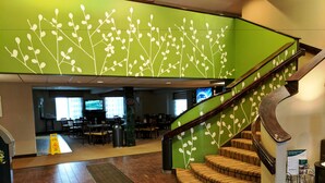 Un hall d’hôtel agrémenté d’un mur végétal, d’un revêtement de sol en bois, d’un escalier et d’un espace détente.
