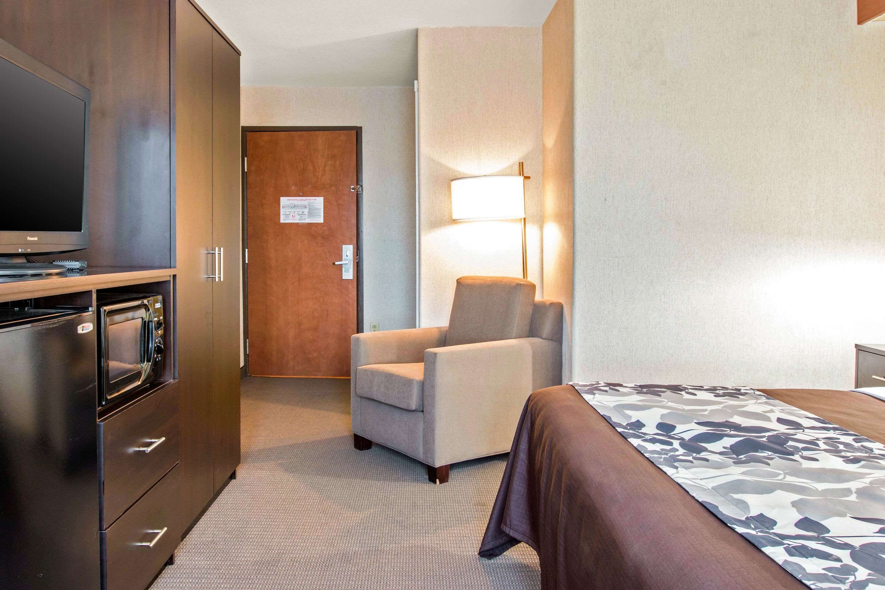 A hotel room with a bed, a TV, a desk, a chair, and a lamp.