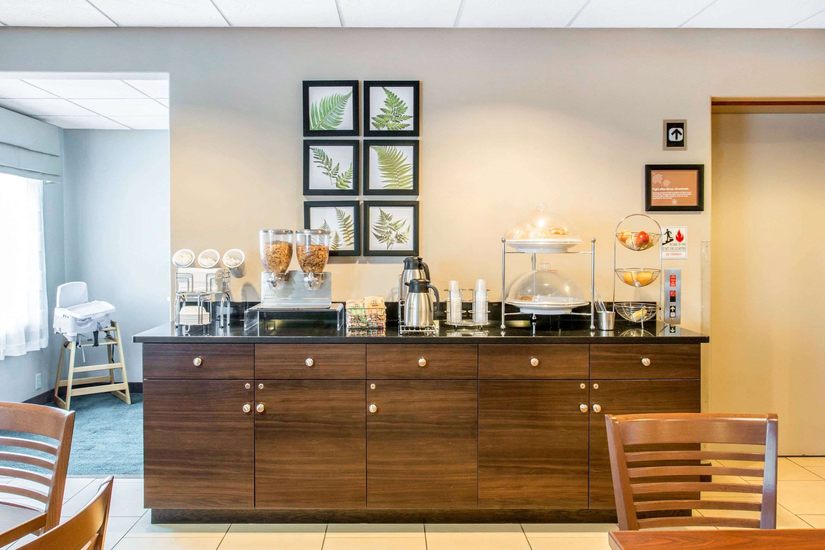 A modern kitchen area with a wooden counter, coffee station, and framed botanical prints on the wall.