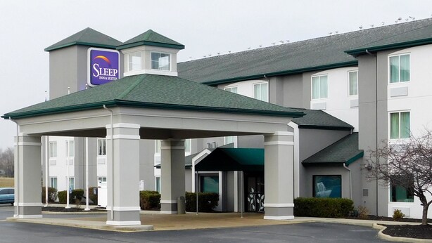 Un bâtiment de la chaîne Sleep Inn & Suites, doté d’une entrée abritée, de nombreuses fenêtres et d’une enseigne sur le toit.