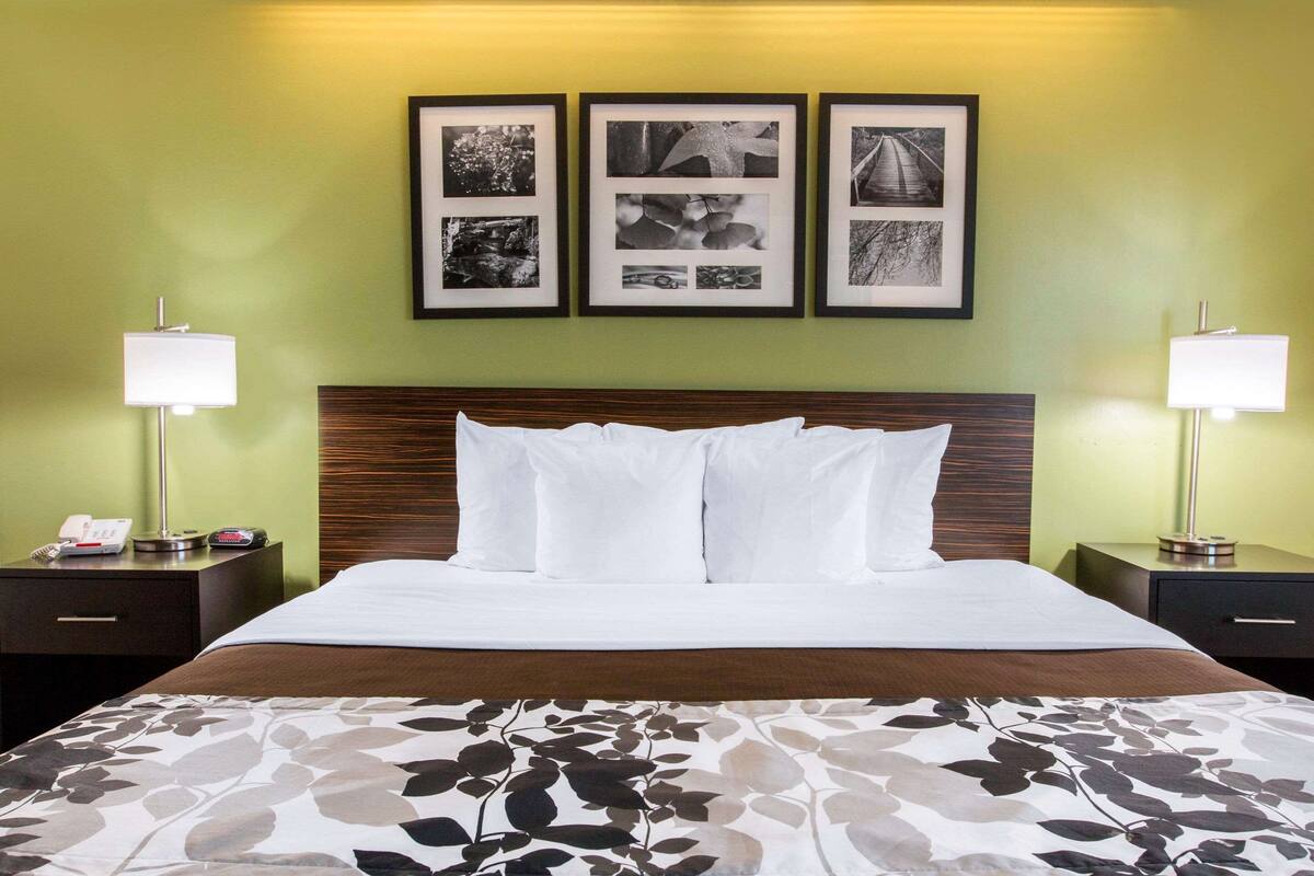 A hotel room with a large bed, two bedside tables, a nightstand, and three framed pictures on the wall.