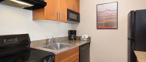 A kitchen with wooden cabinets, a black stove, a microwave, a dishwasher, and a granite countertop.
