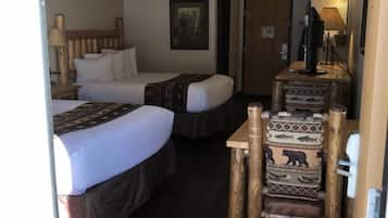 A hotel room with two beds, a desk, and a chair with a bear design.