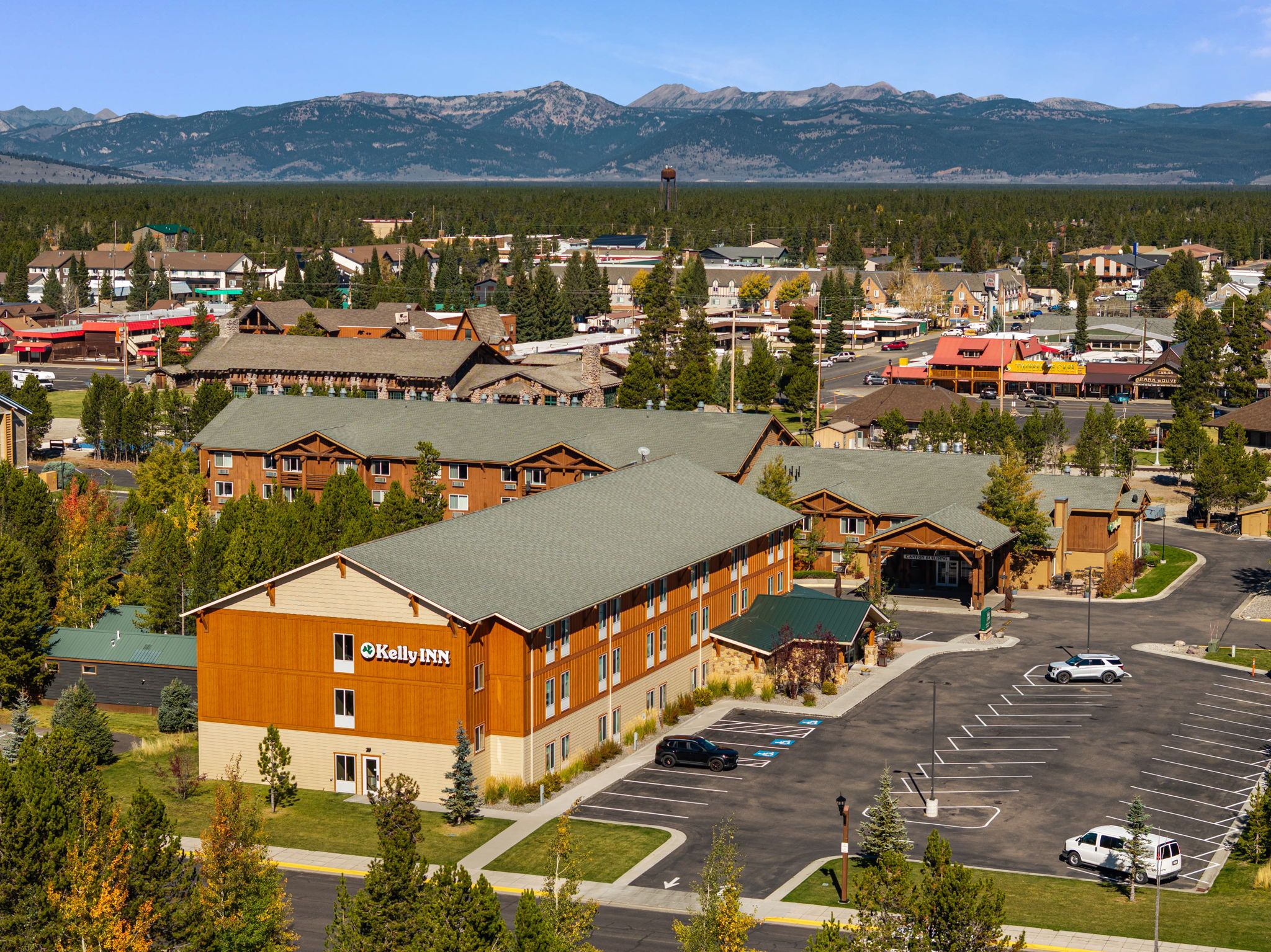 A hotel with a large building, a parking lot, and a mountainous backdrop.
