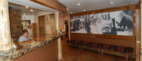 A reception area with a stone wall, wooden beams, a marble counter, and a bench with striped cushions.