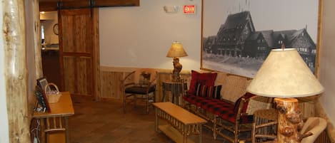 A cozy room with wooden furniture, a lamp, a framed picture, and an exit sign.