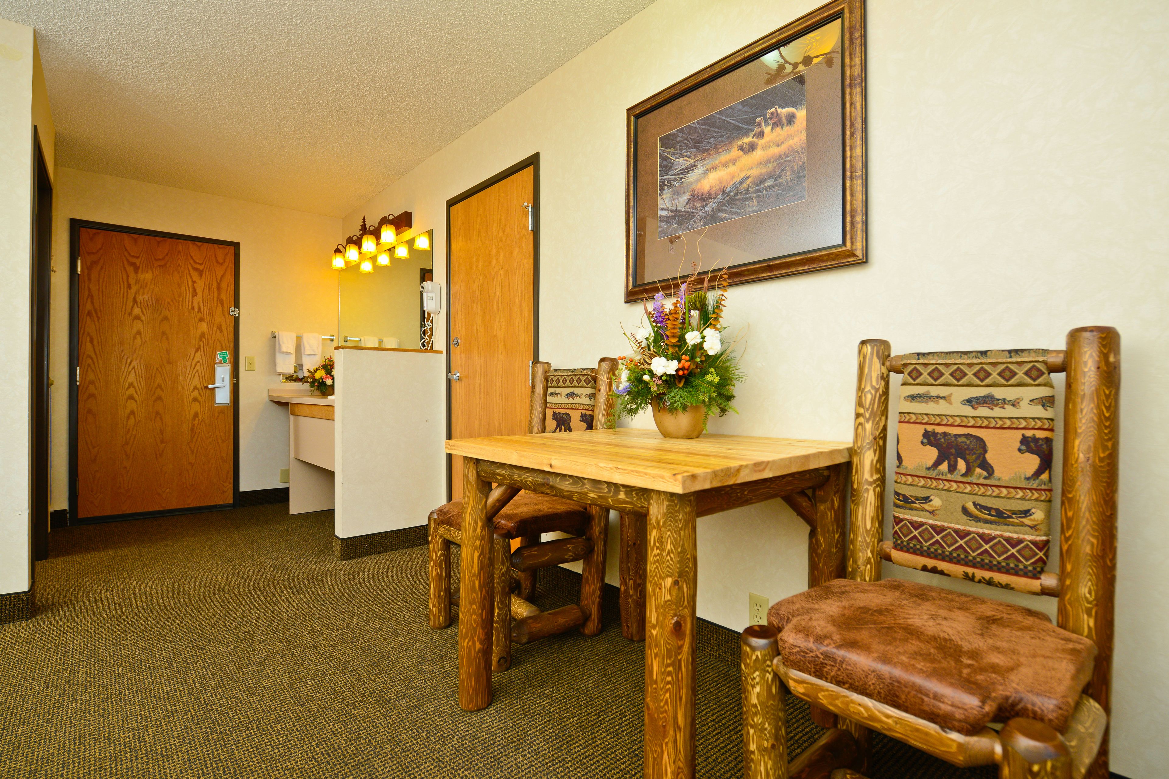A wooden dining table with chairs, a small plant, and a framed picture on the wall.