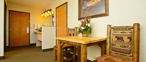 A wooden dining table with chairs, a small plant, and a framed picture on the wall.