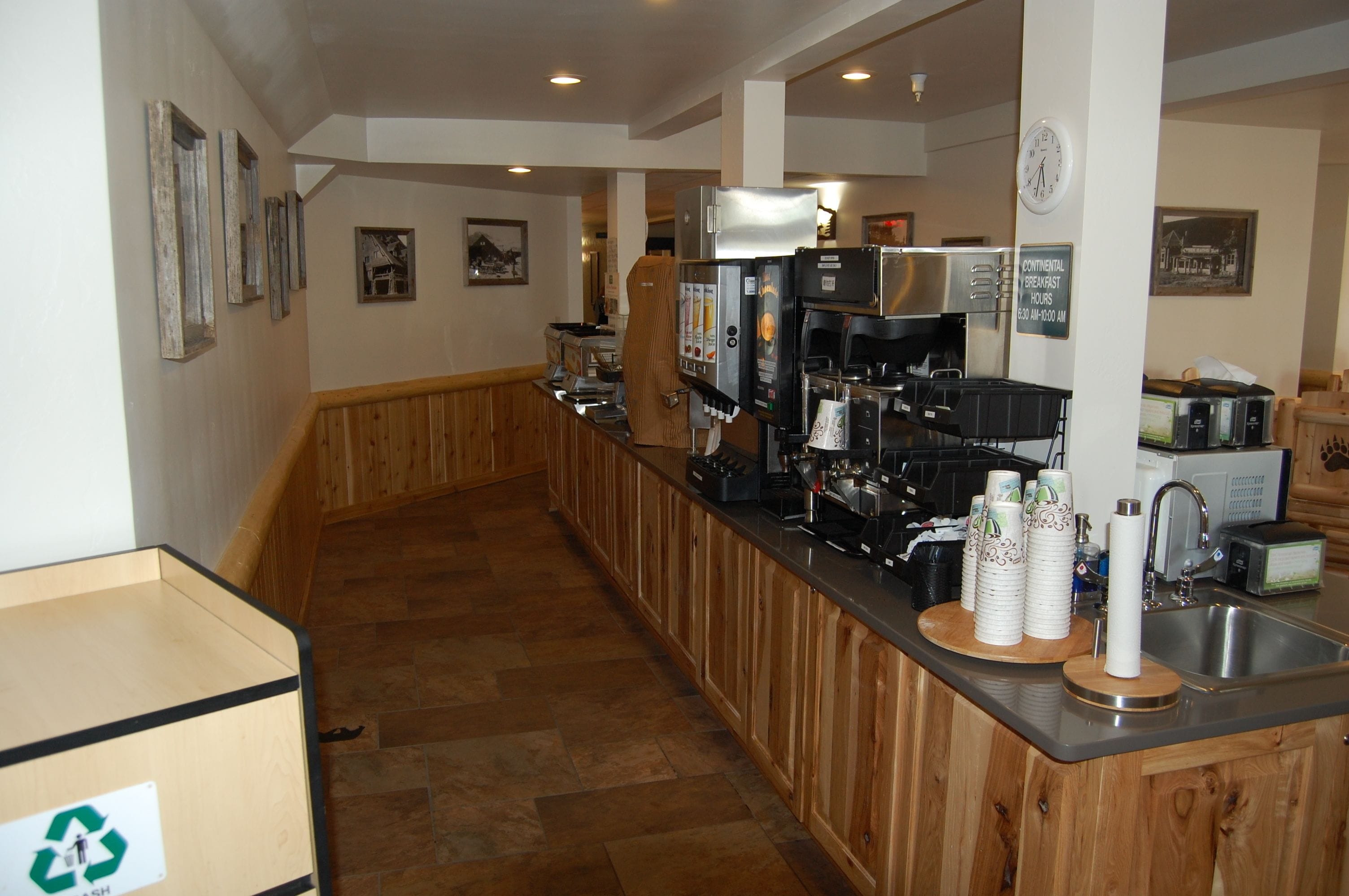 A kitchen area with wooden cabinets, a stainless steel sink, and a coffee machine.