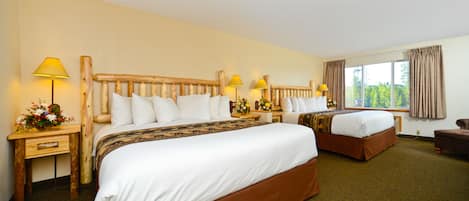 A hotel room with two beds, wooden headboards, and a large window with curtains.
