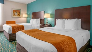 Une chambre d’hôtel avec deux lits, des murs de couleur turquoise et une moquette à motifs.