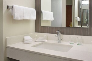 Un baño de hotel con lavamanos, espejo y toallas.