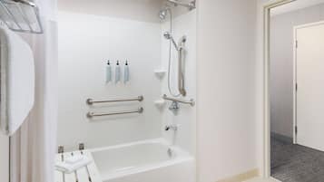 Een moderne badkamer met een witte badkuip, handgrepen, een douchekop en een handdoekrek.