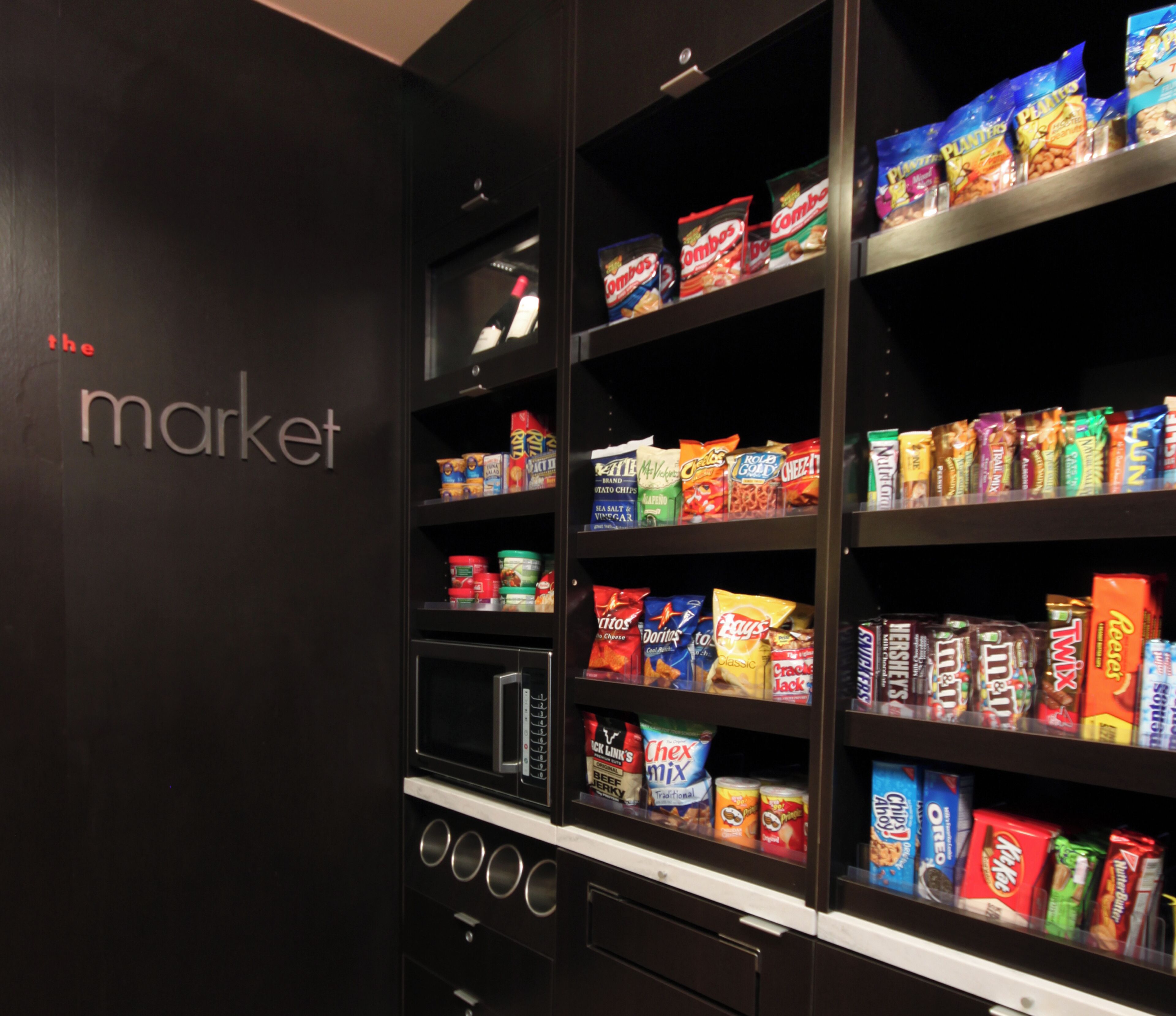 A snack display in a store with various packaged snacks and a microwave.