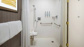 A modern bathroom with a shower, a sink, and a toilet. There are towels on a rack, and toiletries on the wall.