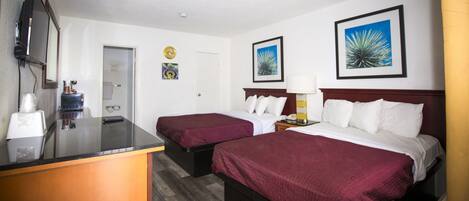 A hotel room with two beds, a desk, a mirror, and artwork on the walls.