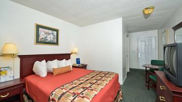 Habitación de hotel con cama, lámparas de noche, televisor, escritorio y silla.