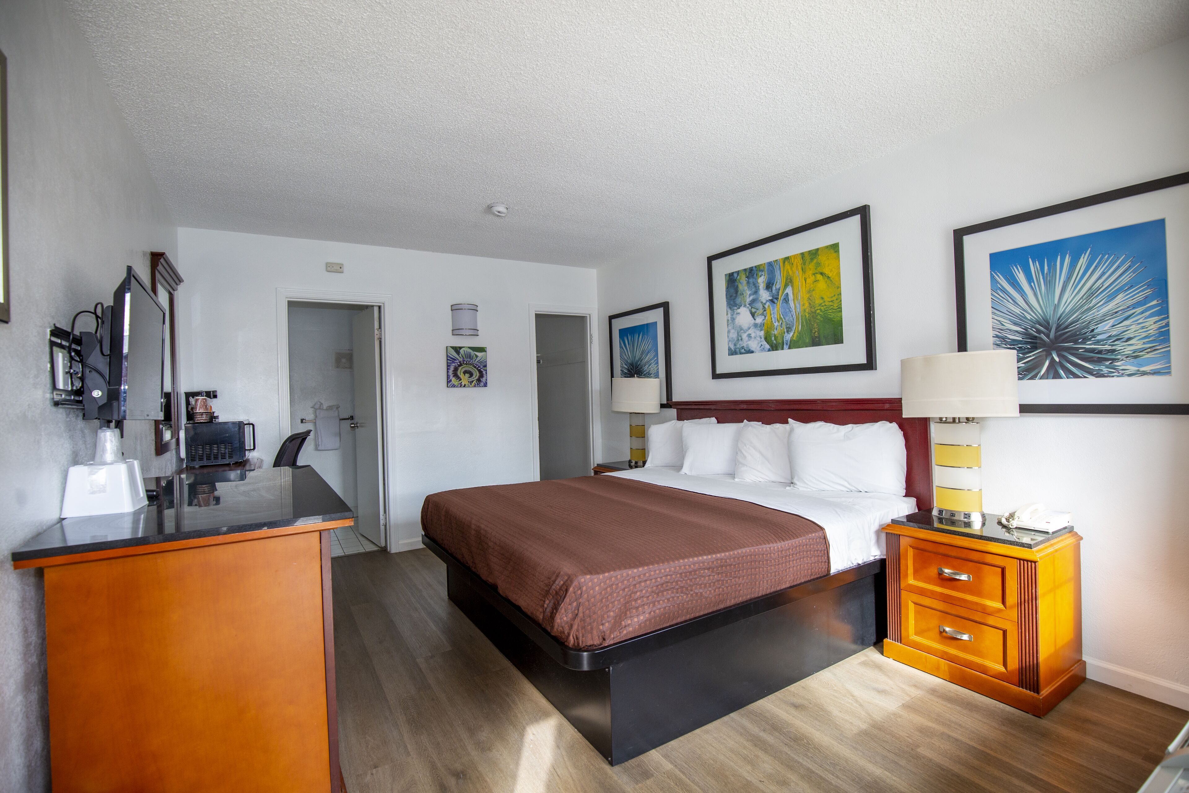 Ein Hotelzimmer mit Bett, Nachttisch, Lampe und Bildern an den Wänden.