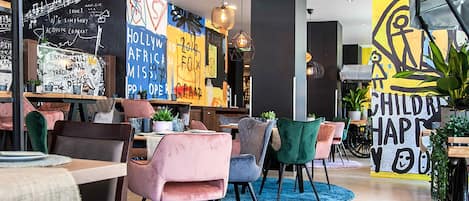 A modern cafe interior with round tables, colorful chairs, and artistic wall decorations.