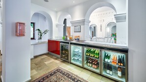 Un hall de hotel con mostrador de recepción, una barra roja y vitrinas de vidrio con bebidas.