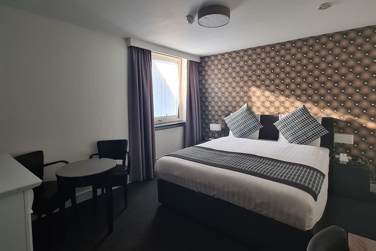 A hotel room with a bed, a desk, and a chair.