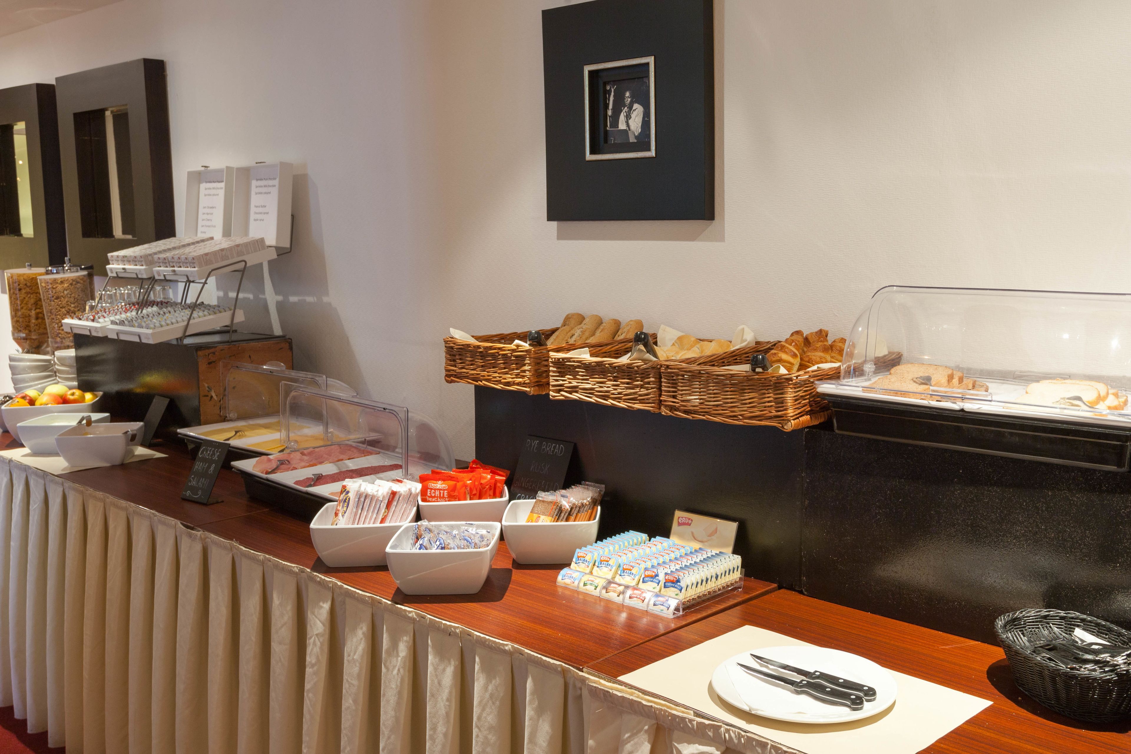 A buffet setup with various food items, including bread, pastries, and dairy products.