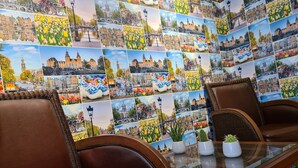 A room with a glass table, brown leather chairs, and a wall covered with a collage of cityscape photographs.