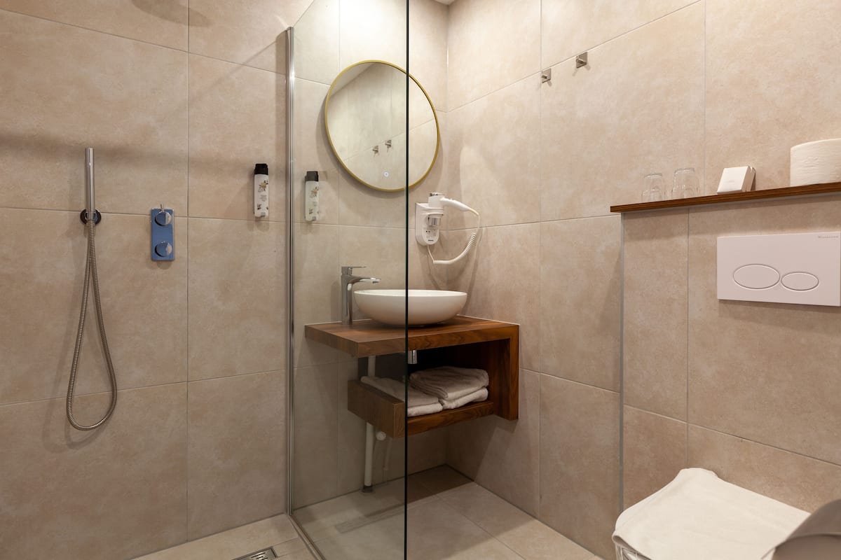 A modern bathroom with a glass-enclosed shower, a wooden vanity with a sink, and a mirror.