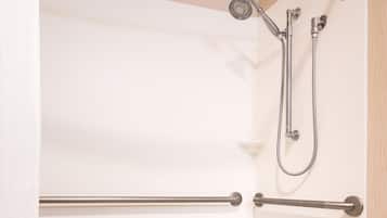 A modern bathroom with a white bathtub, grab bars, and a showerhead.